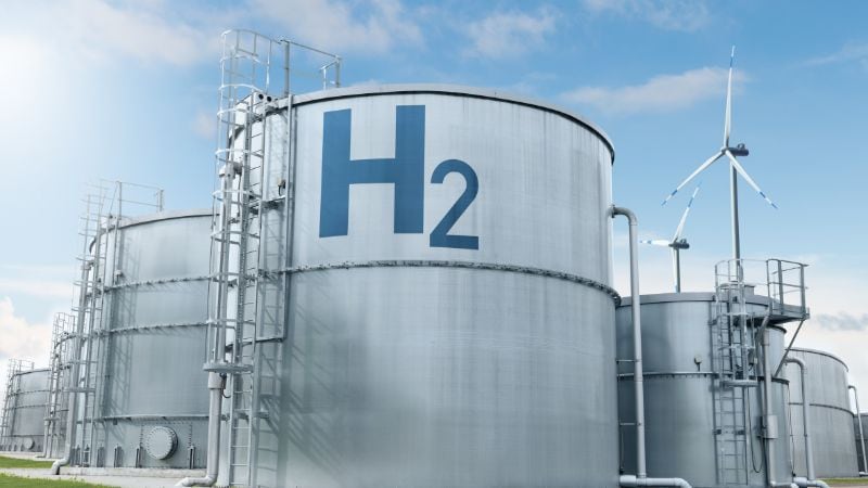 Hydrogen storage tanks at renewable energy facility with wind turbines, clean energy, green hydrogen production, sustainable power, eco-friendly fuel.