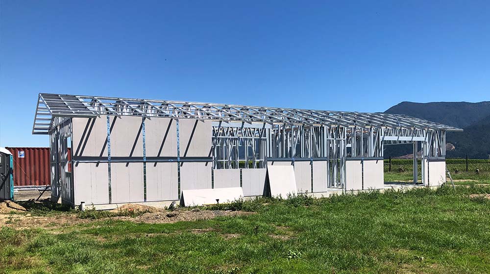 Metal greenhouse under construction with a sturdy frame in a rural area for sustainable gardening and food production.