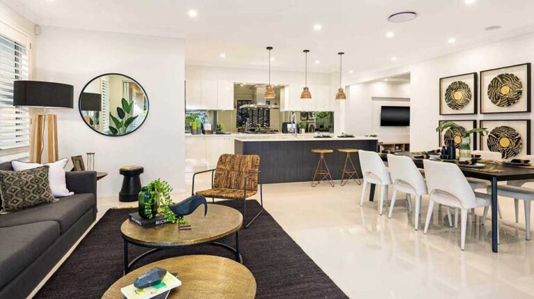 Spacious modern living room with a black sofa, round coffee tables, and a dining area with white chairs, all in a bright, open-plan space.