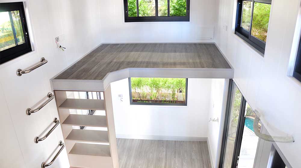 Modern interior of Lecoo tiny house on wheels featuring a loft bed, large windows, and minimalist design for efficient living.
