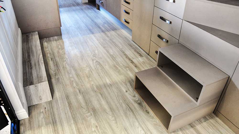 Modern tiny house interior with light wood flooring and compact storage solutions, showcasing efficient use of space in a mobile tiny home.