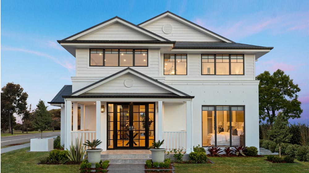 Modern white house with large windows and landscaped front yard, showcasing contemporary architecture and elegant outdoor landscaping.