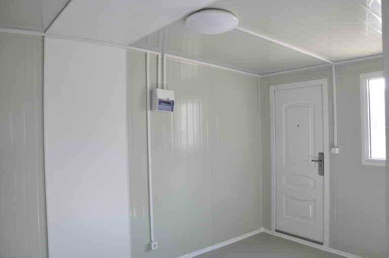 Interno bianco e pulito di una piccola casa portatile con pannelli senza soluzione di continuità, porta moderna, piccola finestra e design compatto, che mette in risalto le parole chiave Casa mobile, Alloggi portatili, Vita in miniatura e Interni moderni.