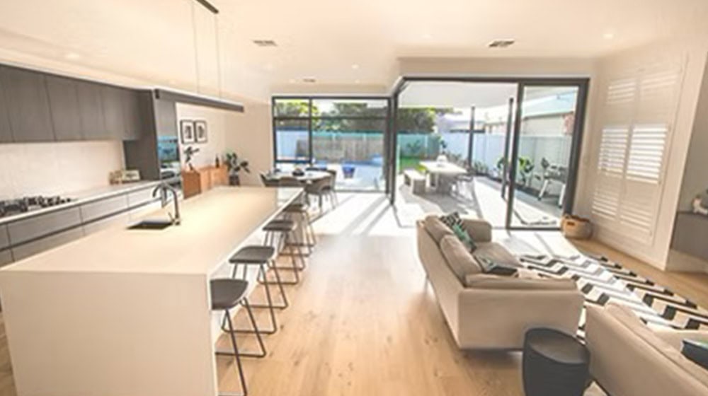 Bright open-concept modern kitchen and living room with large sliding glass doors, stylish furnishings, and natural light, perfect for contemporary home designs and outdoor entertainment.