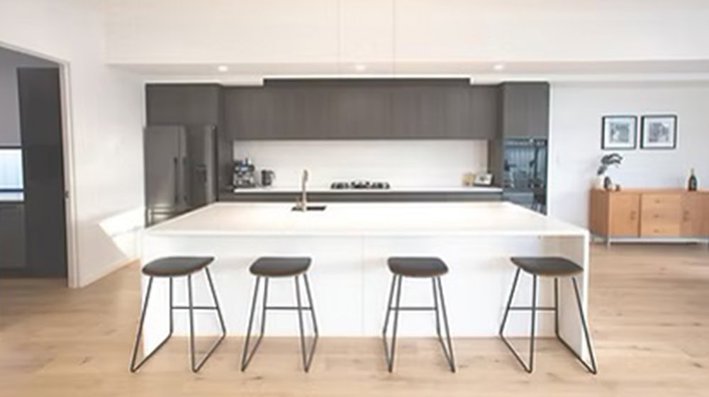 Sleek modern kitchen with white island and black bar stools, minimalist design, contemporary home interior, clean lines, and functional space for cooking and socializing.