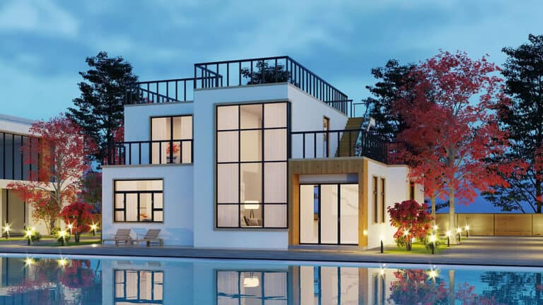 White two-story house with rooftop terrace and large windows, reflected in a pool at dusk among trees.