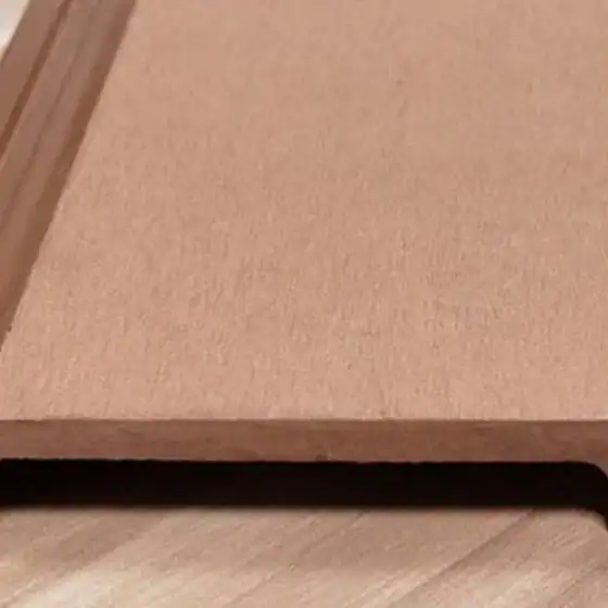 Brown flat wood or MDF panel with a grooved edge, resting on a light-colored wooden surface.