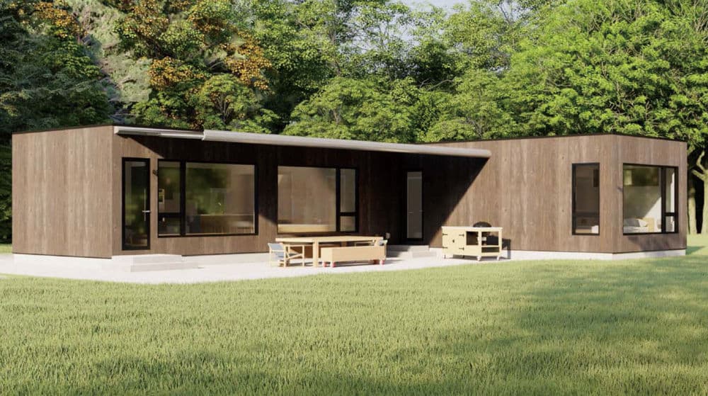 Modern single-story house with dark wood siding, large windows, outdoor furniture, and green grass with trees.