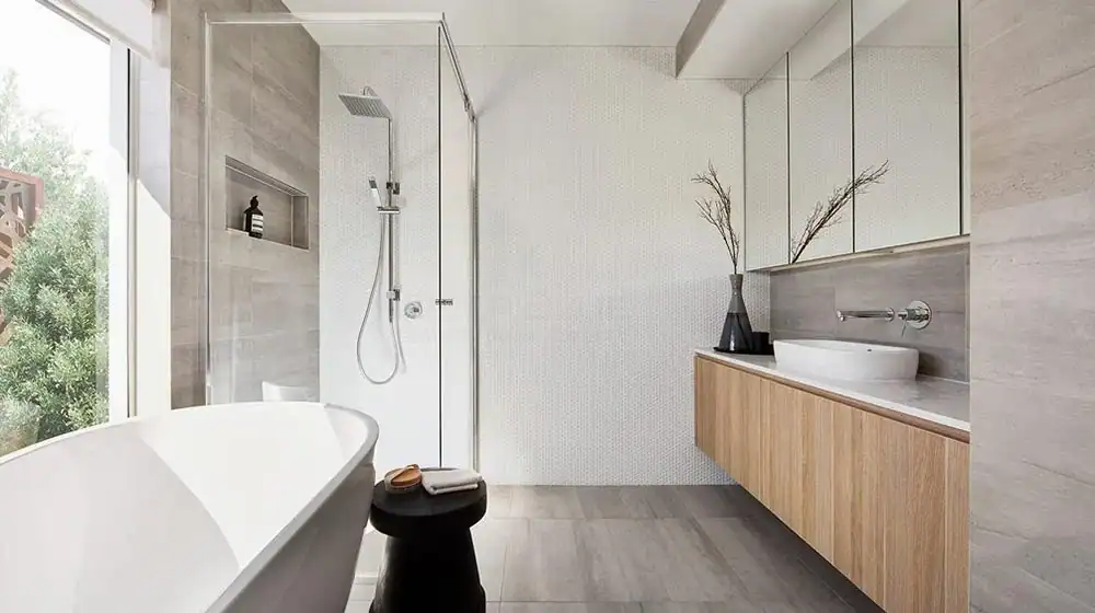 Modern bathroom with freestanding tub, glass shower, floating wood vanity, vessel sink, large mirror, and window light.