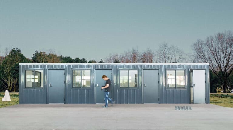 A man standing in front of a large container building.