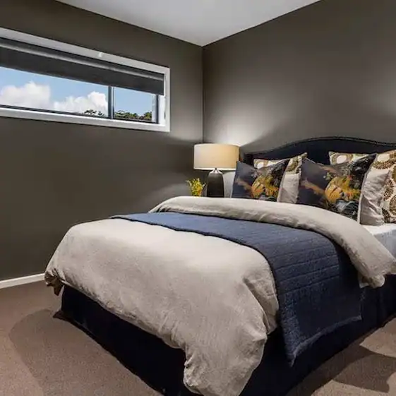 Bed, pillows, and a lamp in a room.