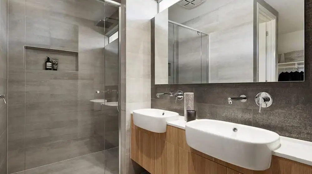 Bathroom with double sink vanity, large mirror, and walk-in glass shower featuring a built-in shelf.