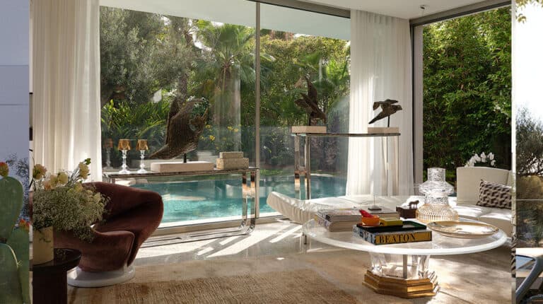 Luxury Bayonne villa living room with large windows, pool view, lush garden, modern furniture, and art decor.