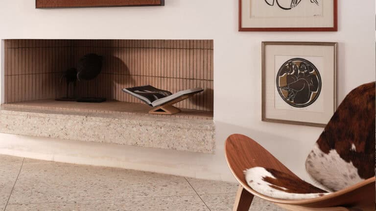 Minimalist villa living space with terrazzo fireplace, open book, modern art, and wood-cowhide accent chair.
