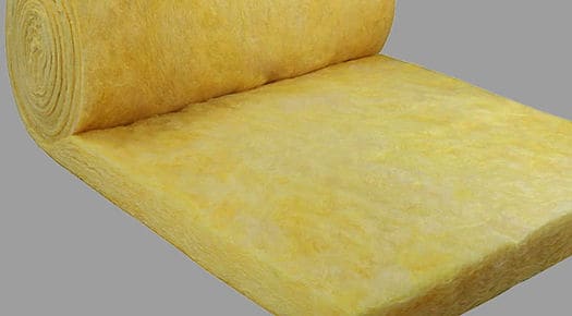 A partially unrolled roll of yellow fiberglass insulation on a gray background.