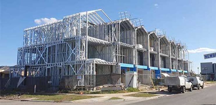 Several multi-story buildings under construction with steel frames exposed; construction vehicles parked nearby.
