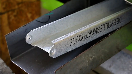 Close-up of a galvanized steel stud with markings on a metal channel, used for construction framing.