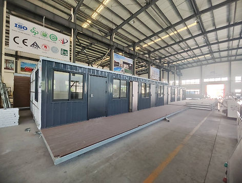 Modular container units lined up in a warehouse, with certification signs visible on the back wall.