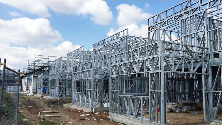 Partially built structures with exposed steel frames and scaffolding beneath a partly cloudy sky.