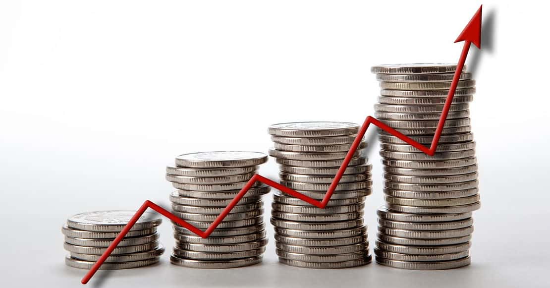 Rising stacks of coins with a red upward arrow, symbolizing financial growth or increasing profits.