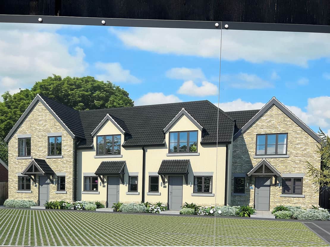 Four modern, two-story townhouses with peaked roofs and landscaped yards under a blue sky.