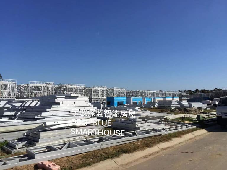 Steel frame construction site with materials on ground, clear sky, and "DEEP BLUE SMARTHOUSE" in English and Chinese.