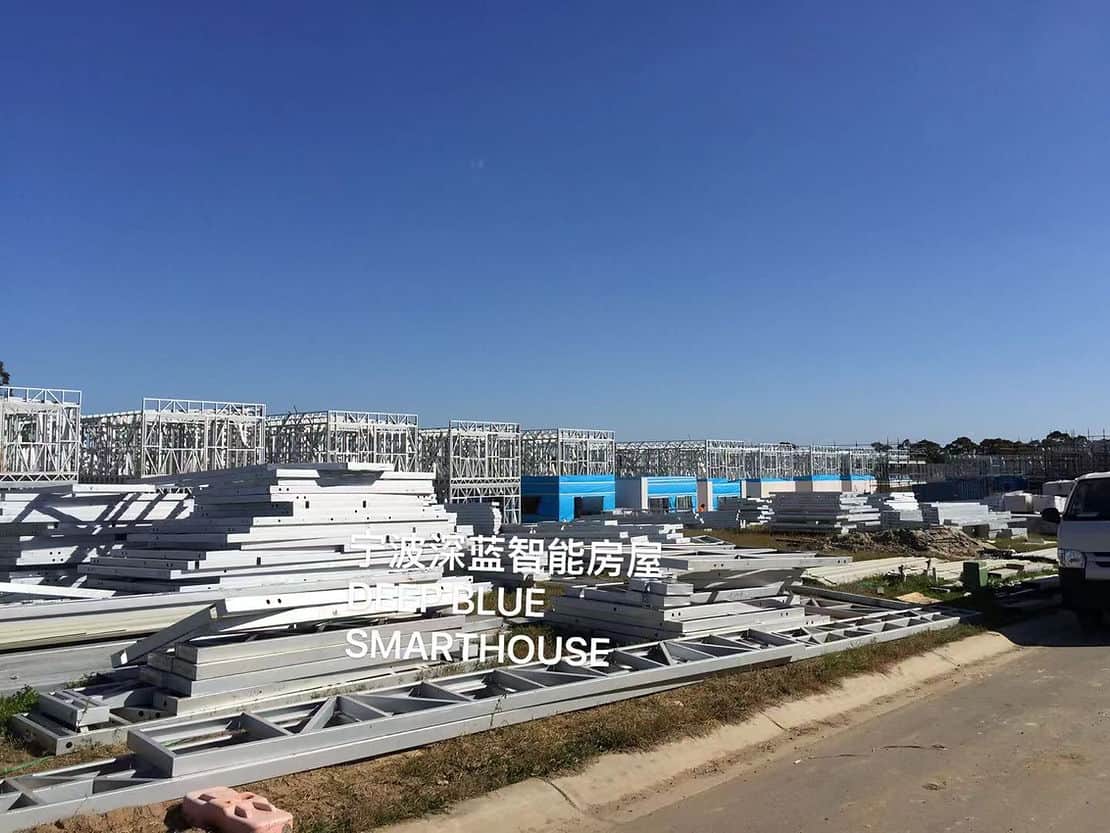 Steel frame construction site with materials on ground, clear sky, and "DEEP BLUE SMARTHOUSE" in English and Chinese.