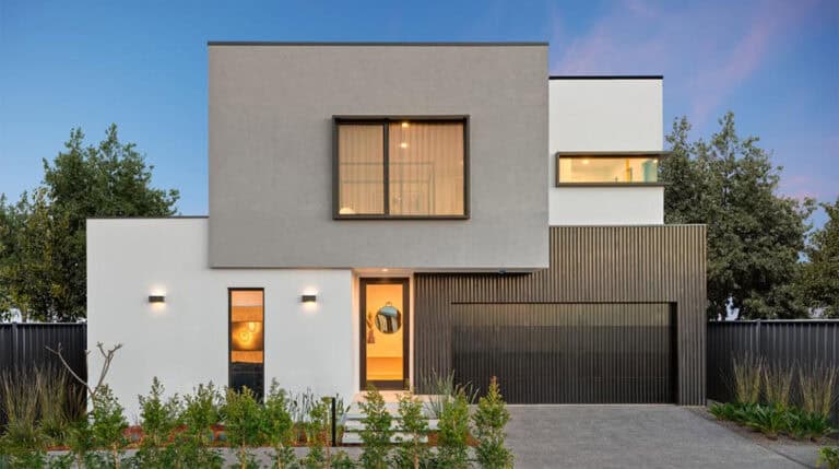 Contemporary modern house with minimalist design, large windows, and mixed exterior textures, surrounded by lush greenery at sunset.