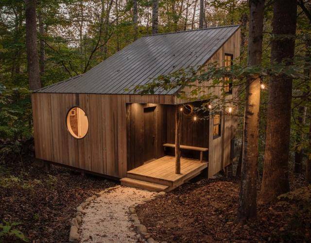 Cozy wooden tiny house nestled in the forest with warm lighting, ideal for sustainable living and backyard retreats.