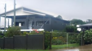 Modern black and gray house with outdoor garden and fence, contemporary residential architecture, stylish home design, lush landscaping, upgraded exterior features.