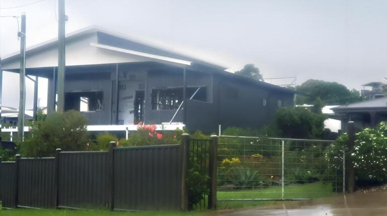 Modern black and gray house with outdoor garden and fence, contemporary residential architecture, stylish home design, lush landscaping, upgraded exterior features.