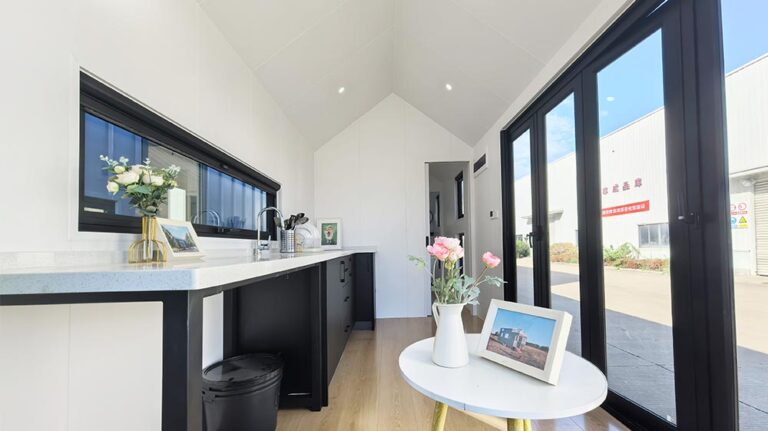 Luminosa cucina moderna con ampie porte scorrevoli in vetro, arredamento minimalista e fiori freschi, che crea uno spazio elegante e arioso, perfetto per uno stile di vita contemporaneo.
