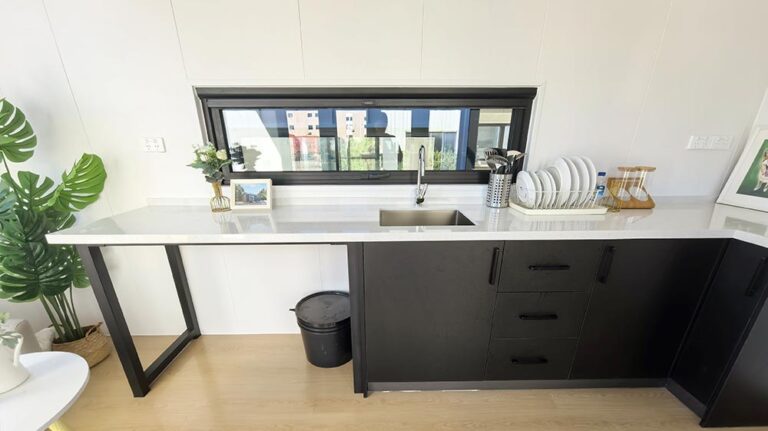 Cucina contemporanea con eleganti mobili bianchi e neri, ampia finestra, moderno scolapiatti e arredamento minimalista, ideale per interni di case moderne.