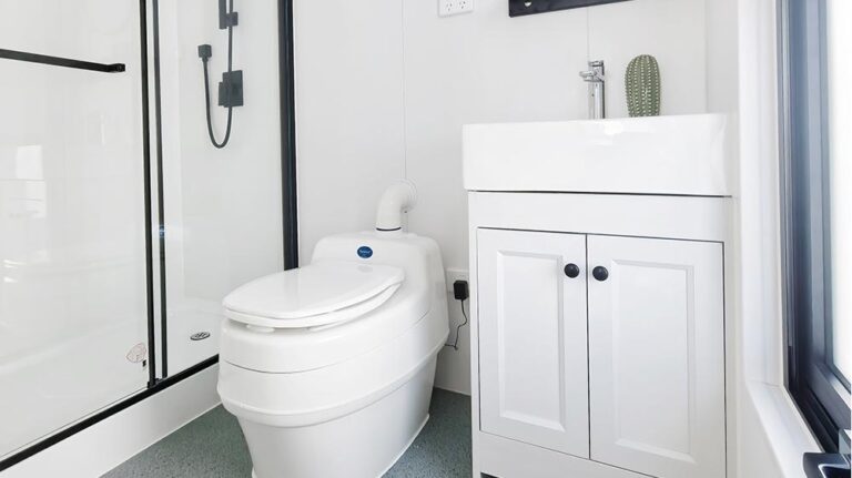 Elegante bagno moderno con bidet high-tech, mobile lavabo bianco, design minimalista e luce naturale proveniente da un'ampia finestra, che enfatizza l'estetica pulita e contemporanea.