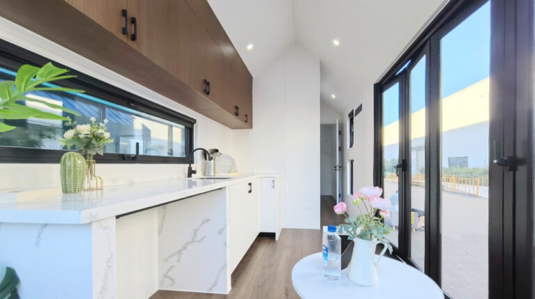 Cucina moderna con ripiani in marmo bianco, mobili in legno, ampie porte scorrevoli in vetro e luce naturale. Perfetta per case contemporanee e spazi abitativi eleganti.