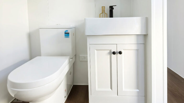 Moderno bagno bianco con elegante water e mobile lavabo minimalista con manopole nere, design pulito e stile contemporaneo, perfetto per gli interni di case moderne.