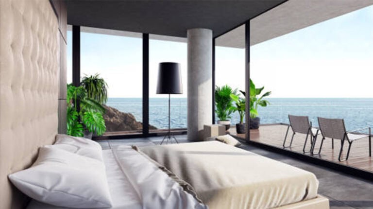 Luxury ocean view bedroom with modern decor and large glass windows showcasing the sea and balcony area.