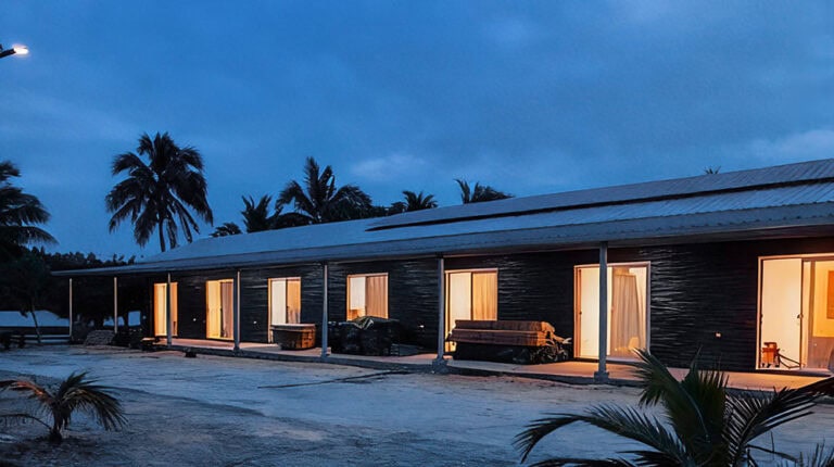 Luxueux bungalow en bord de mer avec intérieurs illuminés, palmiers tropicaux et cadre côtier serein au crépuscule pour une détente et une intimité ultimes.