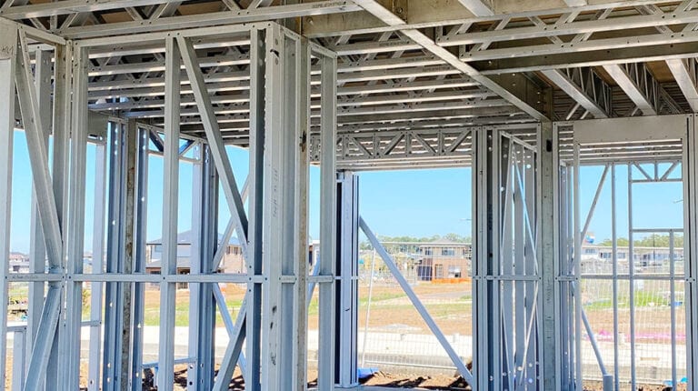 A steel framing structure under construction, showcasing metal studs and framing components, at a residential or commercial building site.