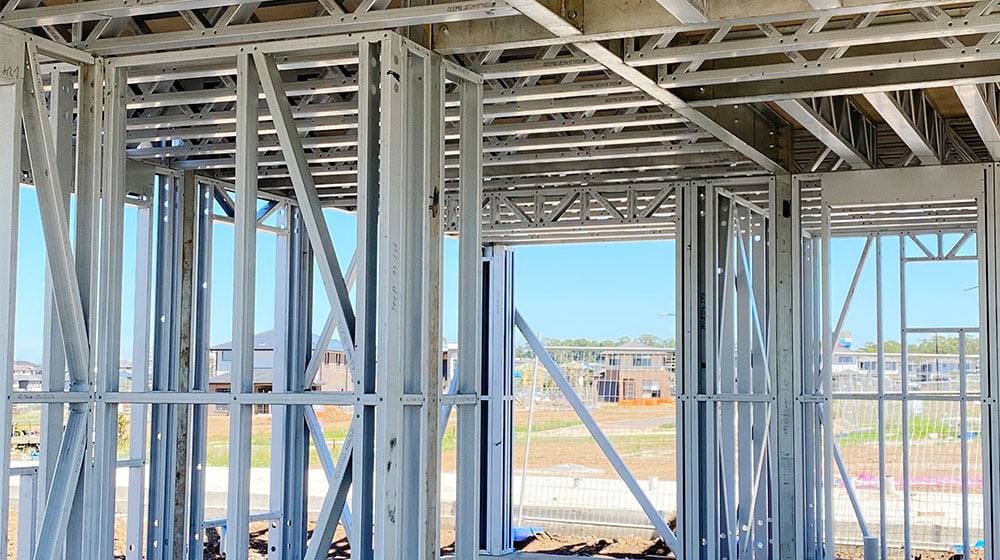 A steel framing structure under construction, showcasing metal studs and framing components, at a residential or commercial building site.