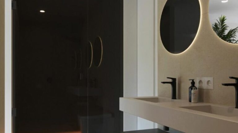 Sleek modern bathroom with dual sinks, black faucets, and stylish round mirrors, featuring contemporary design and ambient lighting for a luxurious and functional space.