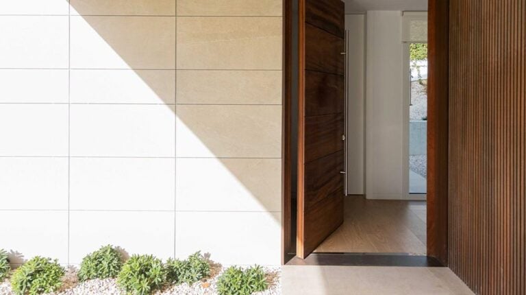Modern minimalist entryway with wood slat accents and clean beige and white tiles, highlighting contemporary home design and exterior decor features.