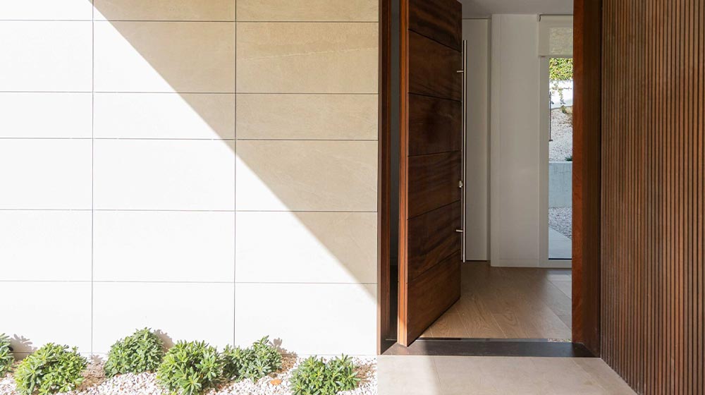 Entrada minimalista moderna con detalles de listones de madera y azulejos limpios de color beige y blanco, que resaltan el diseño contemporáneo del hogar y las características de decoración exterior.