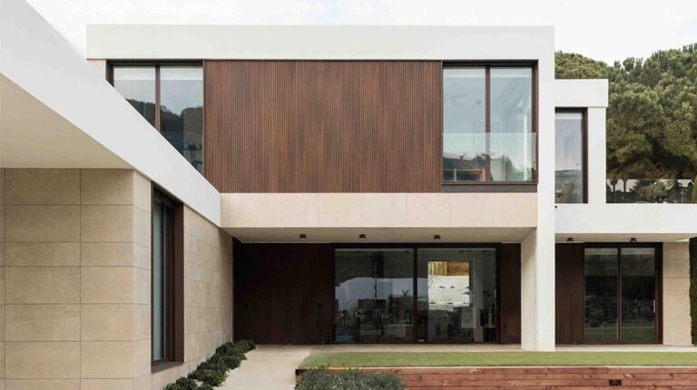 Sleek modern two-story house with large glass windows, white and wooden exterior, and landscaped yard showcasing contemporary architecture and eco-friendly design.