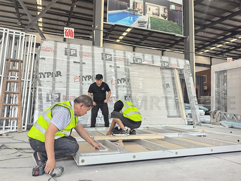 High-quality factory workers assembling modular building components in an industrial warehouse for efficient construction solutions.