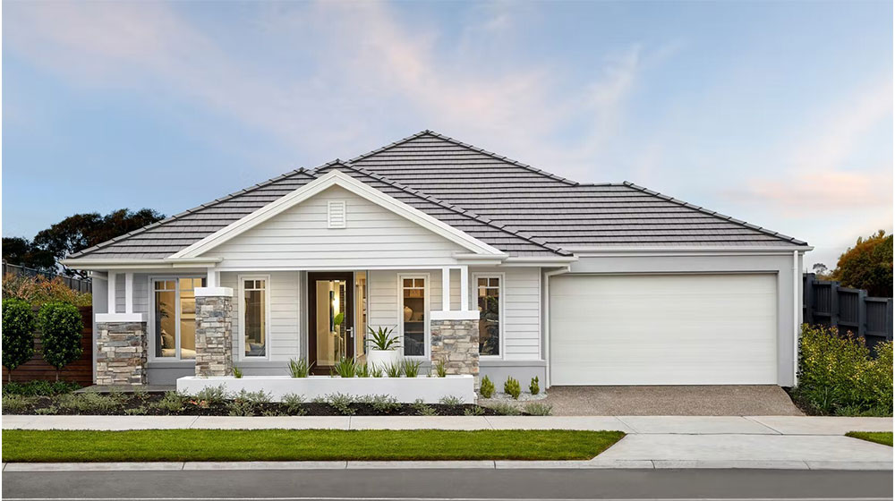 Bright, modern house with white siding, stone accents, and a spacious garage, set in a well-maintained yard with lush greenery, showcasing high-quality roofing and siding options.