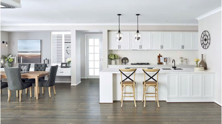 Bright, open-concept kitchen and dining room with white cabinets, modern lighting fixtures, and elegant decor, ideal for stylish and functional living spaces.