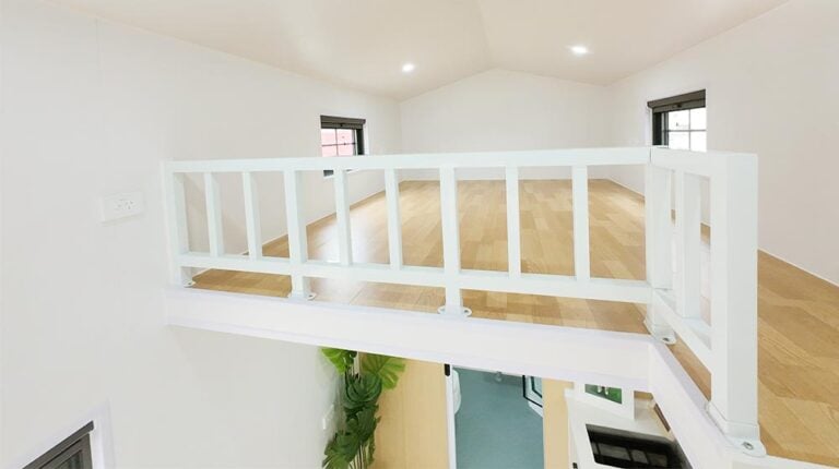 Spacious interior with white walls, wooden floors, large windows, and a safety railing, highlighting modern home design and renovation elements for a stylish living space.