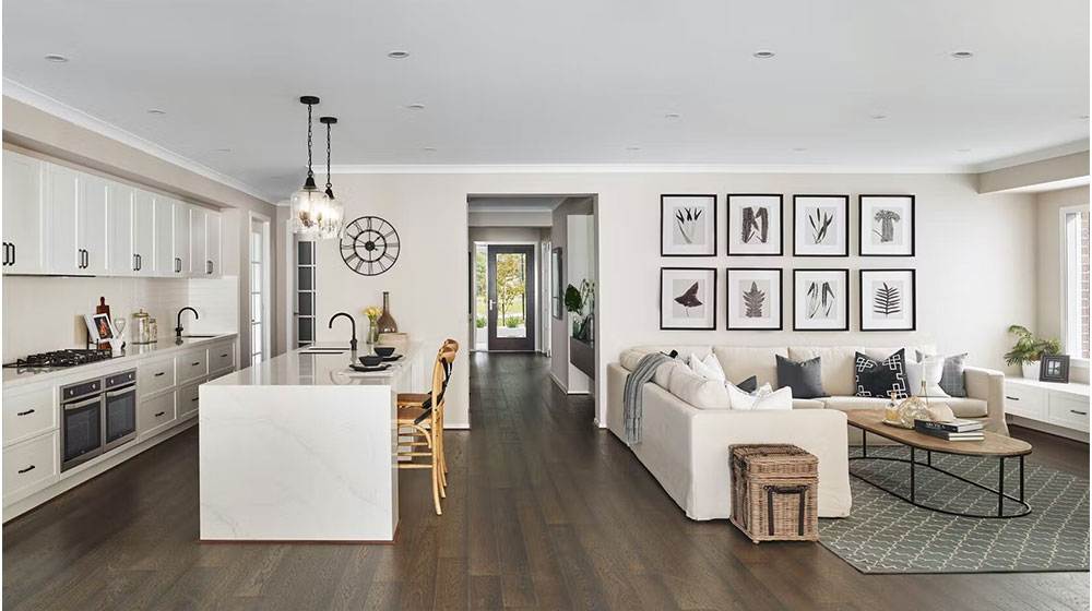 Bright and airy living room with open kitchen, white cabinetry, dark hardwood floors, stylish wall art, and cozy seating area, perfect for a contemporary coastal home.
