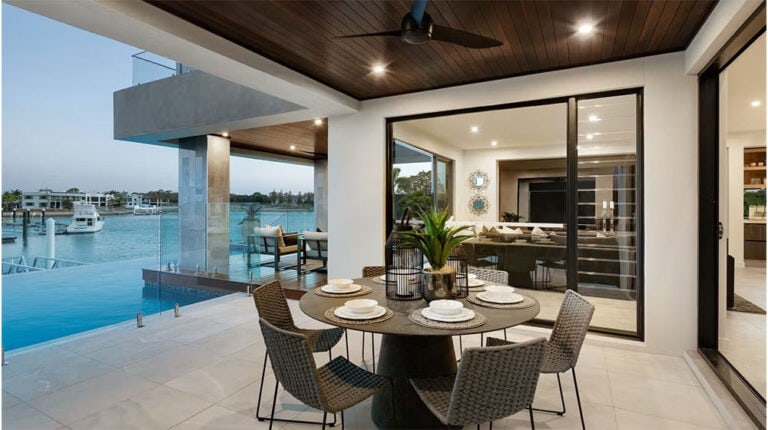 Spacious balcony with outdoor dining, overlooking water, modern design, and stylish furniture for waterfront living.